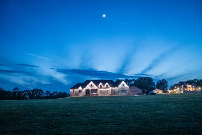 A beautifully lit home stands against a twilight sky filled with clouds