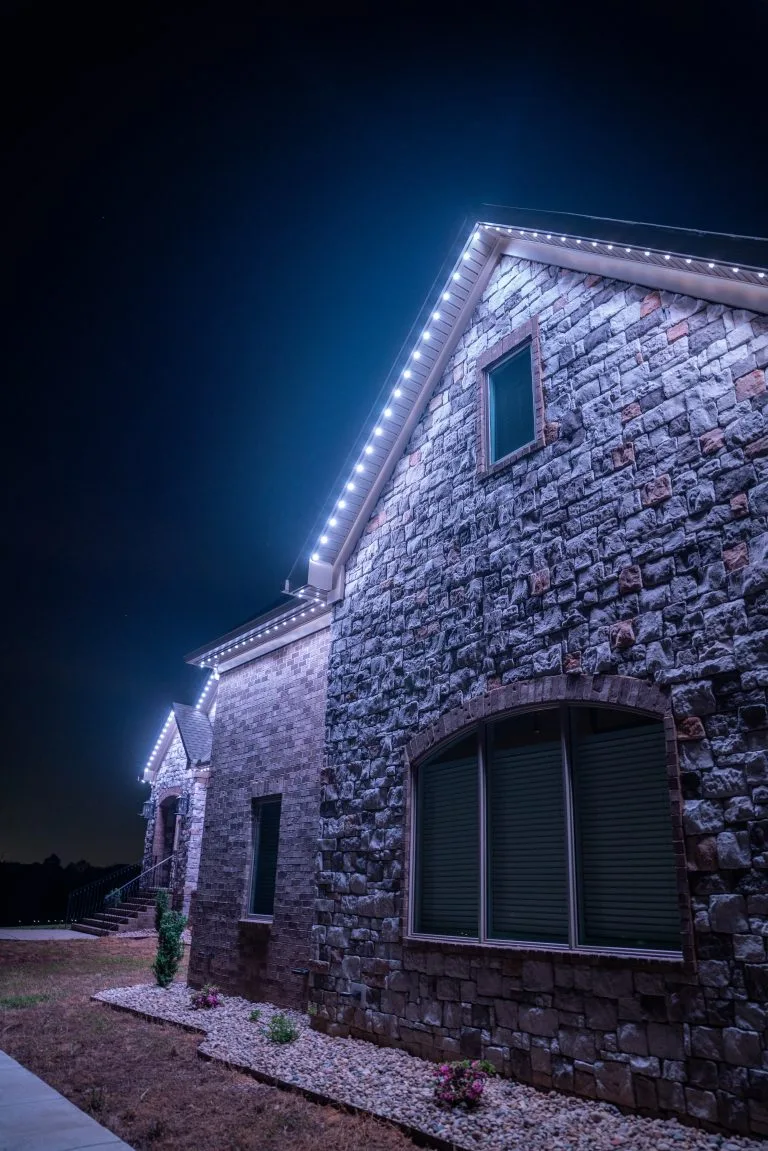 A stone house is illuminated with bright lights against a dark night sky