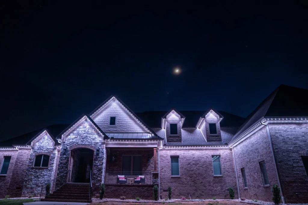 Gemstone lights illuminate a house near West End, Tennessee, under a crescent moon in the night sky
