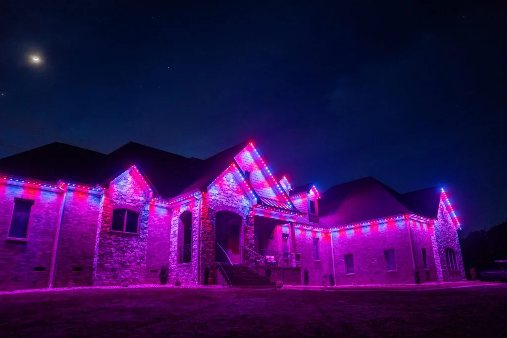 Roofline lighting enhances the grand building's beauty with vibrant pink and purple hues at night
