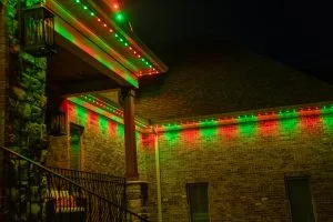 Permanent Christmas lights near Buckhead Atlanta illuminate a brick house with vibrant red and green colors at night
