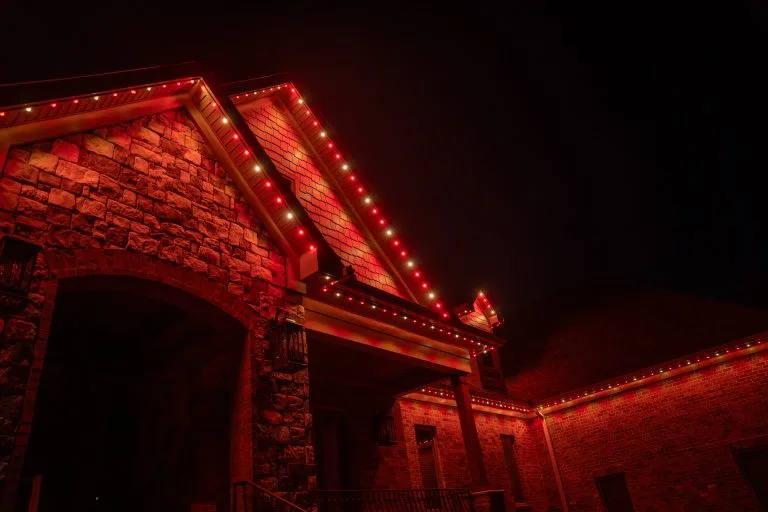 A stone house is illuminated with bright red lights against a dark sky