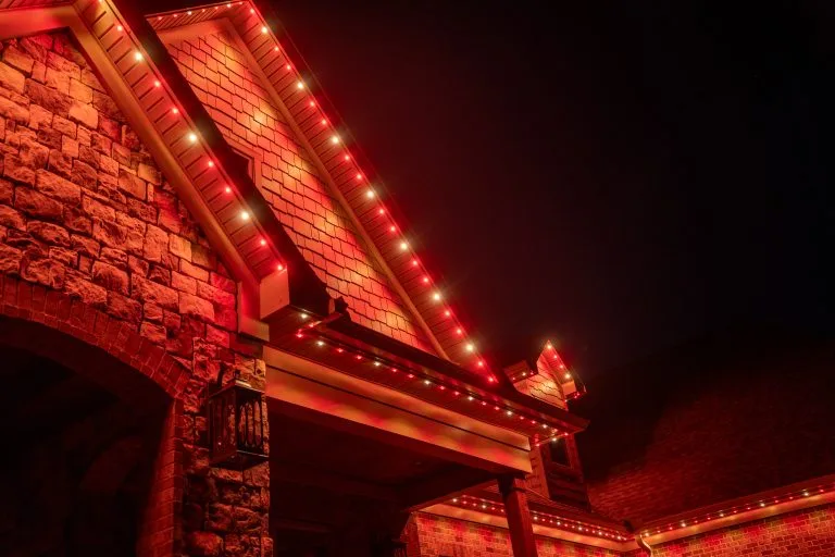 A house is adorned with vibrant red lights against a dark sky