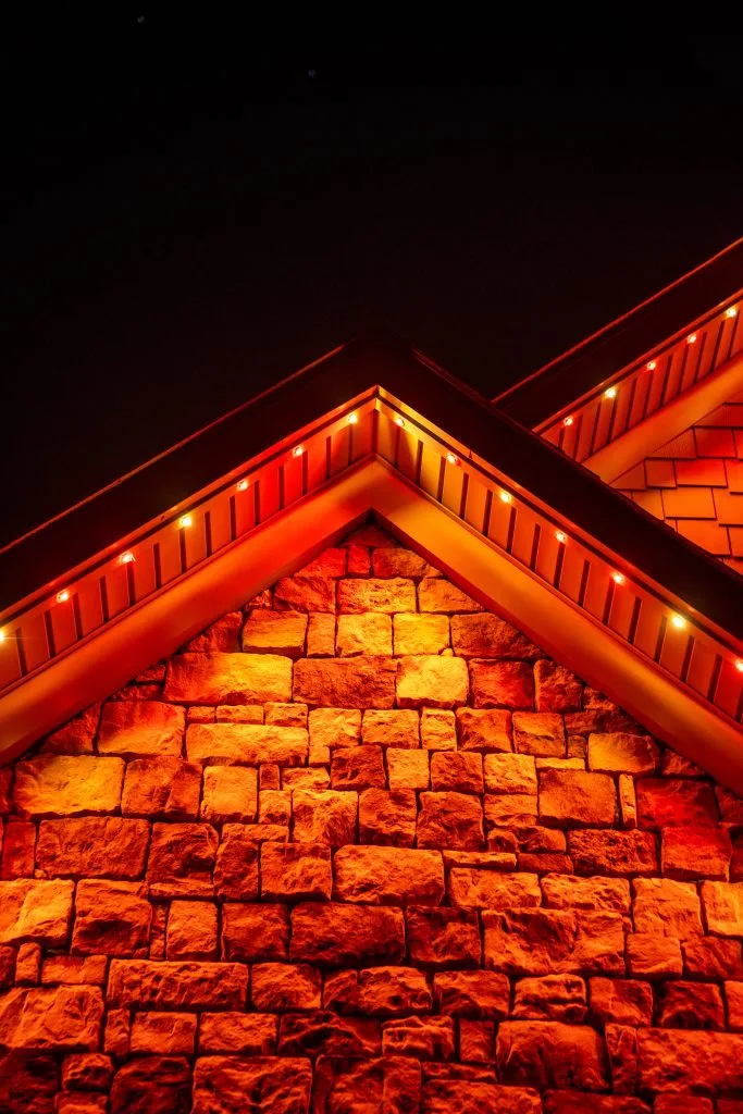 Soffit & under-eave lighting near Ansley Park Atlanta highlights illuminated stone walls against a dark sky