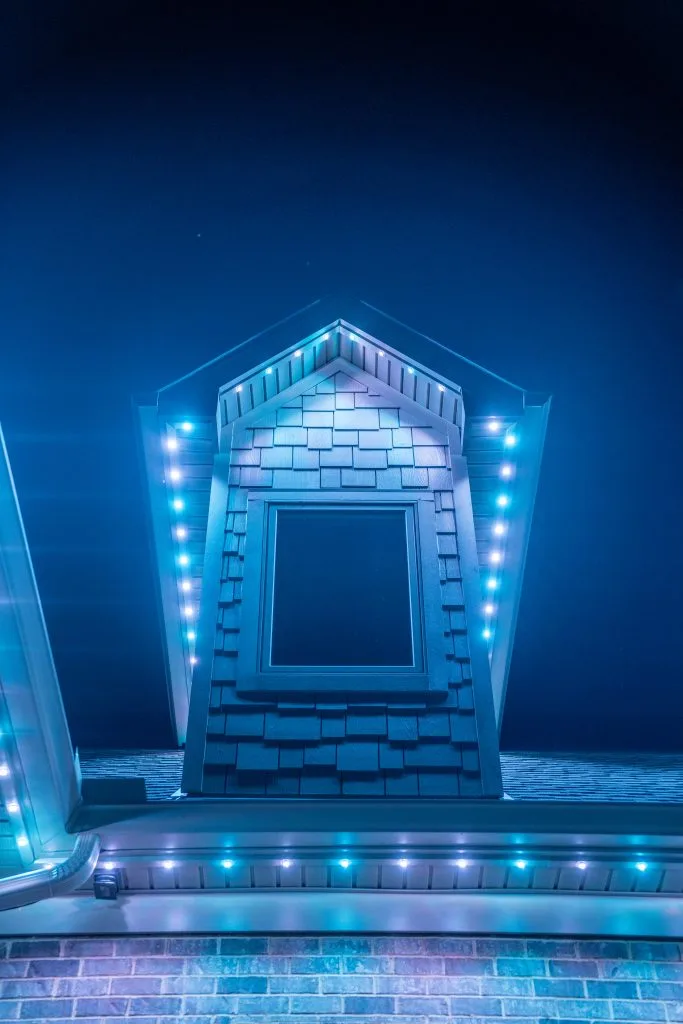 Soffit LED lights illuminate a decorative window on a brightly lit rooftop at night