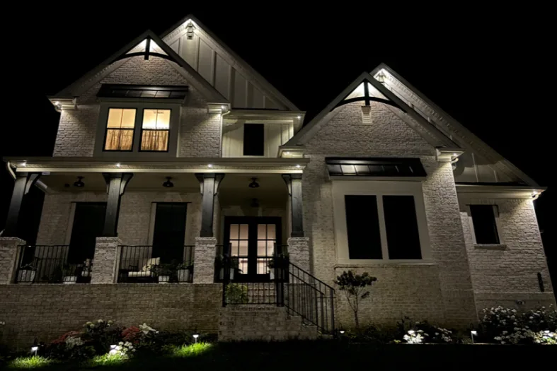 A well-lit modern house stands elegantly at night, showcasing its architectural details