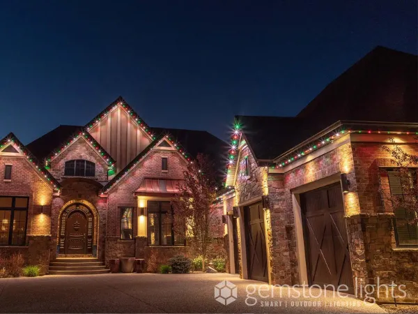 Permanent Christmas lights illuminate a festively decorated house at twilight