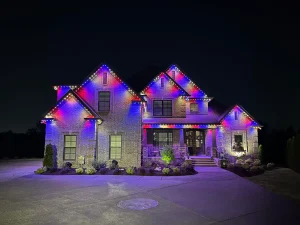 A beautifully lit house is adorned with colorful lights against a dark night sky